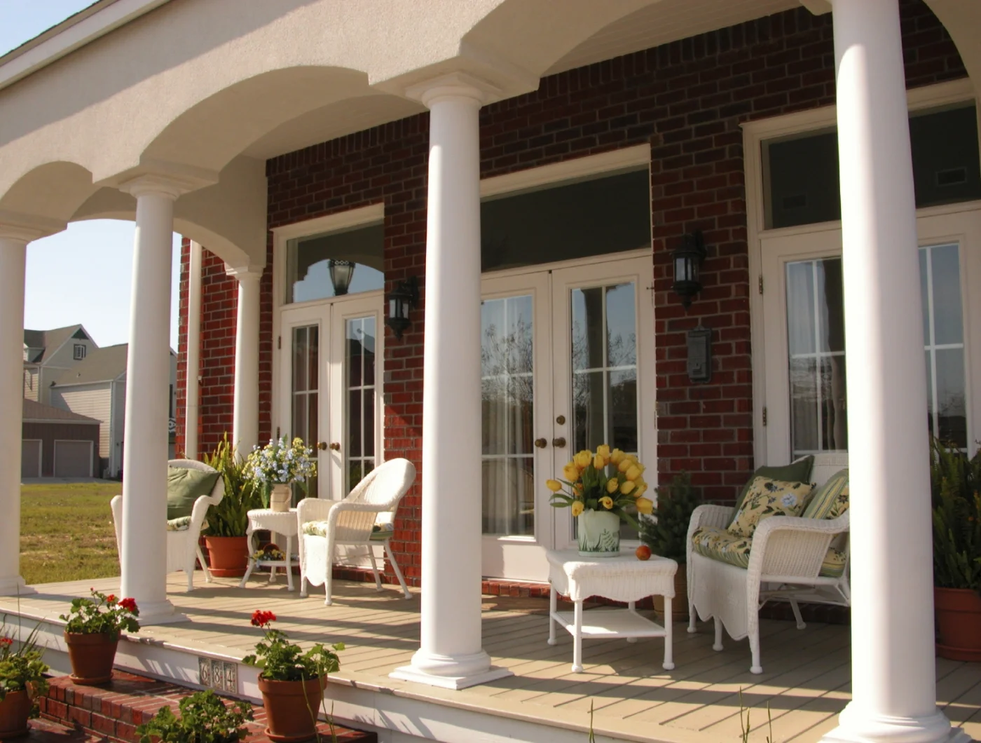 Finished cellular PVC columns, deck, and trim installed on a classic brick home porch built by Patwin Plastics customers.